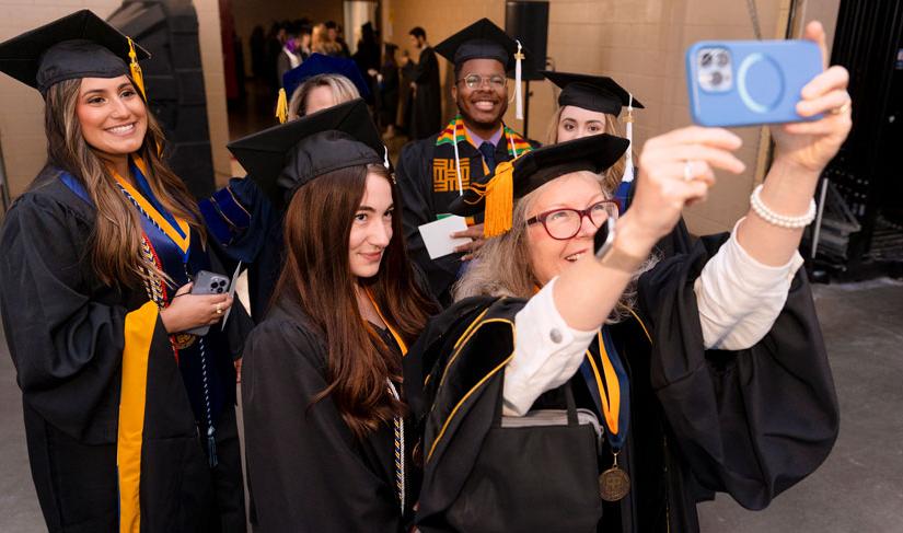 St. 爱德华大学的毕业生们在进入2022年毕业典礼前摆姿势自拍